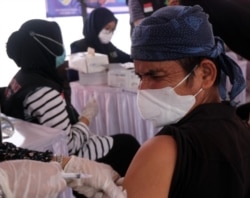 Seorang Baduy Luar menahan sakit ketika disuntik vaksin Covid-19 oleh petugas kesehatan pada acara Vaksinasi Peduli Baduy yang berlangsung pada 14-15 Oktober 2021 di Ciboleger, Banten. (Foto: VOA/Indra Yoga)