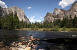 FILE - A youngster walks along the banks of the Merced River, in view of El Capitan (L), and Bridalveil Fall (R) in Yosemite National Park, California May 17, 2009.