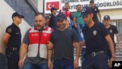 Turkish police officers escort Turkish pop singer Atilla Tas, center, to police headquarters following his arrest, in Istanbul. Tas and 28 other people, mostly journalists, went on trial Monday, March 27, 2017, on terrorism charges for alleged links to a failed coup attempt. 