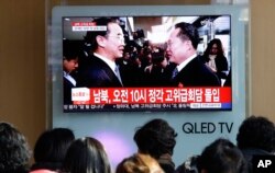 People watch a TV screen showing South Korean Unification Minister Cho Myoung-gyon, left, meets with the head of North Korean delegation Ri Son Gwon