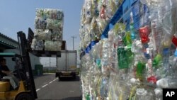 FILE - Packs of flattened polyethylene terephthalate (or PET) bottles are carried into a depot before being pulverized as part of a recycling process at Tokyo PET Bottle Recycle Co. in Tokyo, Aug. 13, 2002. 