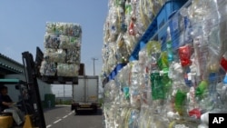 FILE - Packs of flattened polyethylene terephthalate (or PET) bottles are carried into a depot before being pulverized as part of a recycling process at Tokyo PET Bottle Recycle Co. in Tokyo, Aug. 13, 2002. Researchers in Britain and the United States have engineered an enzyme that breaks down such plastics. 