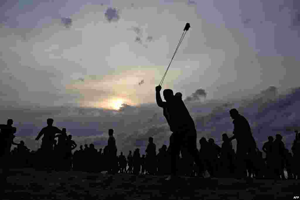 A Palestinian protester throws a stone towards Israeli forces during clashes on the beach near the maritime border with Israel, in the northern Gaza Strip.