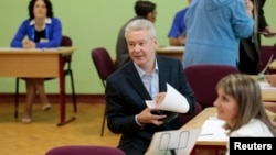 Current Moscow mayor Sergei Sobyanin (C) fills out his ballot before voting at a polling station in Moscow September 8, 2013.