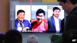 FILE - In this May 3, 2018 photo, people watch a TV news report on screen, showing portraits of three Americans, Kim Dong Chul, left, Tony Kim and Kim Hak Song, right, detained in the North Korea. (AP Photo/Ahn Young-joon)