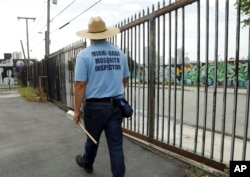 FILE - An inspector with the Miami-Dade County mosquito control department, looks for standing water as he inspects an empty lot in the Wynwood neighborhood of Miami, Florida, Aug. 2, 2016.