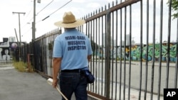 An inspector with the Miami-Dade County mosquito control department, looks for standing water as he inspects an empty lot, Aug. 2, 2016, in the Wynwood neighborhood of Miami, Florida.