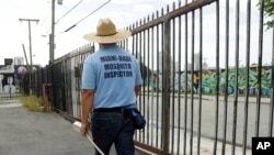 FILE - An inspector with the Miami-Dade County mosquito control department, looks for standing water as he inspects an empty lot, Aug. 2, 2016, in the Wynwood neighborhood of Miami, Florida.