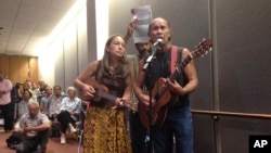 FILE - In this June 23, 2014 file photo, Laulani Teale, left, and Liko Martin, right, sing while Palani Vaughan, center rear, holds up a copy of Queen Liliuokalani's protest of the overthrow of Hawaii at the Hawaii state Capitol in Honolulu. 