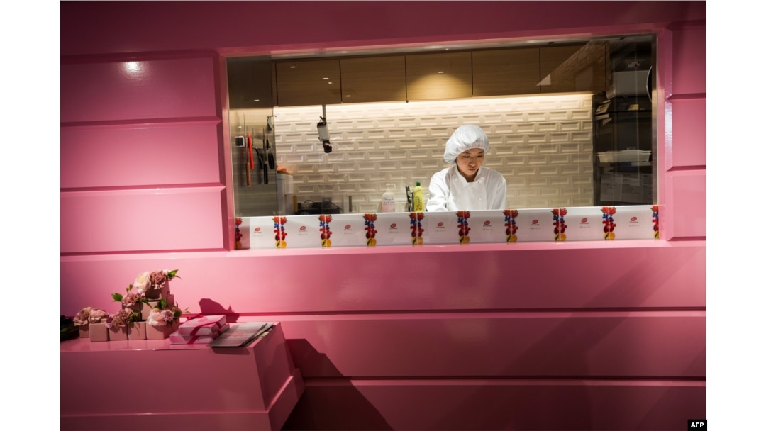 Seorang karyawan menyiapkan pesanan pelanggan di toko cokelat KitKat, dengan dinding bercat merah mudah untuk promosi cokelat rubi merah muda KitKat di Tokyo, 7 Februari 2018.