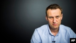 In this photo provided by Alexei Navalny's campaign, Russian opposition leader Alexei Navalny records a video for his YouTube channel in his office in Moscow, Russia, July 7, 2017.