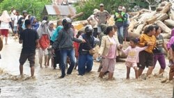 Warga masyarakat desa Rogo, Dolo Selatan, Kabupaten Sigi, Sulawesi Tengah berjalan kaki di jalan raya yang terendam air banjir bandang yang menyebabkan 70 rumah terendam dan 200 jiwa mengungsi, 15 September 2020. (Foto: VOA/Yoanes Litha)