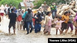 Warga masyarakat desa Rogo, Dolo Selatan, Kabupaten Sigi, Sulawesi Tengah berjalan kaki di jalan raya yang terendam air banjir bandang yang menyebabkan 70 rumah terendam dan 200 jiwa mengungsi, 15 September 2020. (Foto: VOA/Yoanes Litha)
