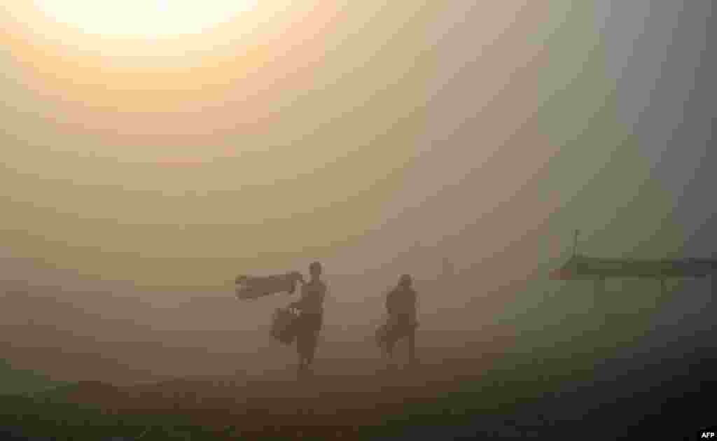 Penganut Hindu India berjalan melalui badai debu setelah melakukan penyucian diri di Sangam, pertemuan Sungai Gangga, Yamuna dan Saraswati yang mistis, di Allahabad. &nbsp;