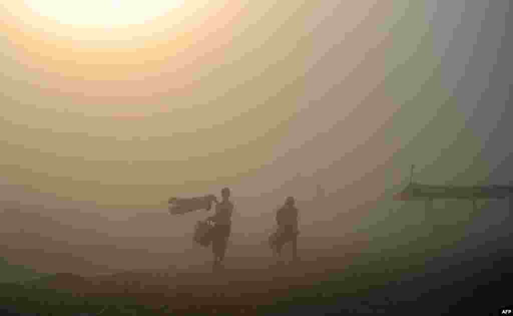 Indian Hindu devotees walk through a dust storm after taking a holy dip at the Sangam, the confluence of the rivers Ganges, Yamuna and mythical Saraswati, in Allahabad.