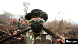 Tentara Indonesia menggunakan kacamata renang untuk melindungi matanya dari asap saat membantu memadamkan kebakaran hutan di desa Parit Indah, Kampar, Riau (8/9). (Reuters/YT Haryono)