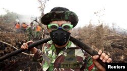 Personil TNI dan warga berusaha memadamkan kebakaran hutan di desa Parit Indah, Kampar, Riau bulan lalu (foto: dok).