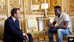 French President Emmanuel Macron, left, meets with Mamoudou Gassama, 22, from Mali, at the presidential Elysee Palace in Paris, Monday, May, 28, 2018. 