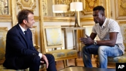 French President Emmanuel Macron, left, meets with Mamoudou Gassama, 22, from Mali, at the presidential Elysee Palace in Paris, May, 28, 2018.