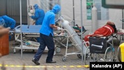 Seorang petugas medis mendorong tangki oksigen yang akan digunakan untuk merawat pasien di tenda darurat yang didirikan untuk menampung lonjakan kasus COVID-19, di RSUP Dr Sardjito Yogyakarta, Minggu, 4 Juli 2021. (AP Photo/Kalandra)