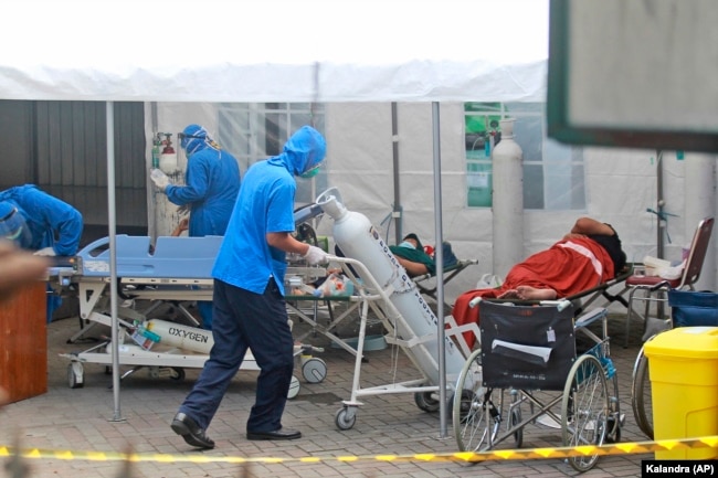 Seorang petugas medis mendorong tangki oksigen yang akan digunakan untuk merawat pasien di tenda darurat yang didirikan untuk menampung lonjakan kasus COVID-19, di RSUP Dr Sardjito Yogyakarta, Minggu, 4 Juli 2021. (AP Photo/Kalandra)