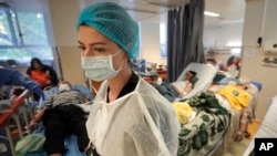 FILE - A member of the medical staff walks in a crowded COVID-19 isolation room at the University Emergency Hospital in Bucharest, Romania, Oct. 22, 2021.