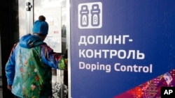 Un homme passe devant une pancarte du contrôle antidopage, au Centre de ski lors des Jeux Olympiques d'hiver de 2014 à Krasnaya Polyana, Russie.