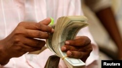 FILE - A Somali man counts his money at a Dahabshiil money transfer office in "Kilometer Five" street of Soobe village, southern Mogadishu, May 8, 2013.