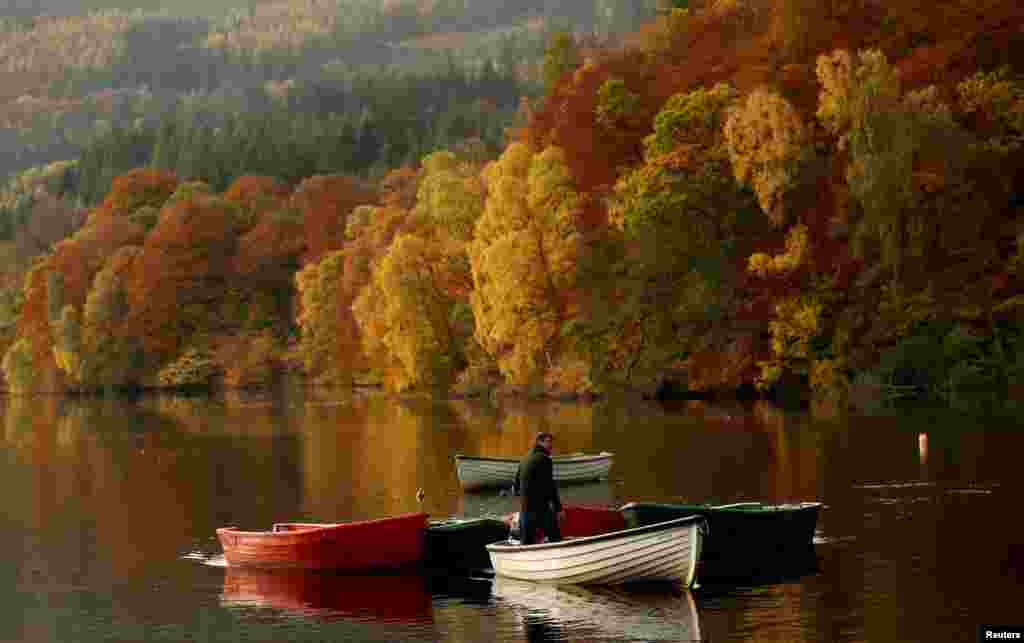 단풍잎으로 물든 영국 스코트랜드의 파스칼리 인공호수에서 남성이 배 위에 선 채 주변을 감상하고 있다.