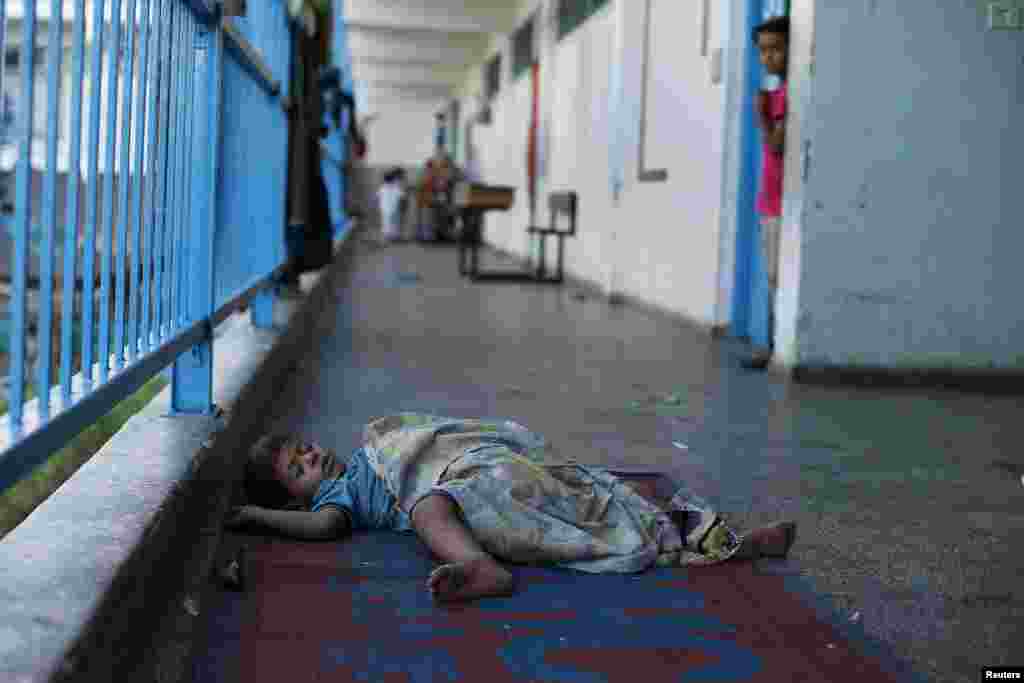 A Palestinian boy sleeps at a United Nations-run school that shelters Palestinians displaced by the Israeli offensive, in Beit Lahiya town, in the northern Gaza Strip, Aug. 12, 2014.