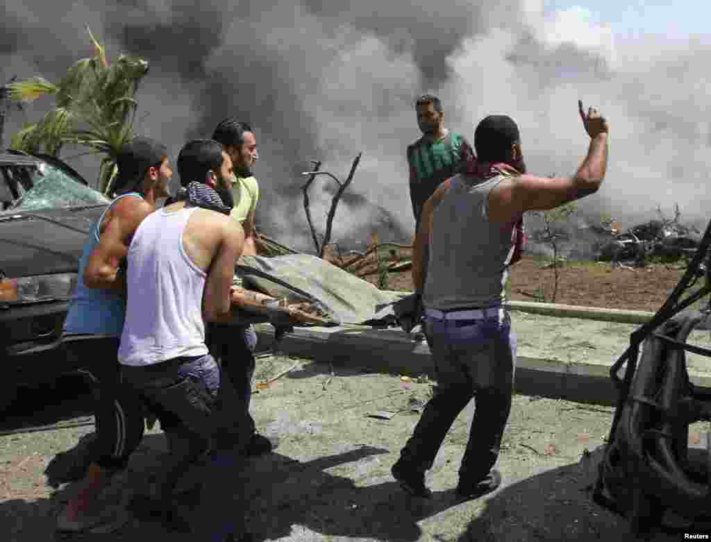 People carry a body outside one of two mosques hit by explosions in Lebanon's northern city of Tripoli, August 23, 2013.