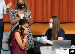 Ariel Quero (16, left), a student at Lehman High School, is injected with the Pfizer COVID-19 vaccine by Katrina Taormina (right), in New York, July 27, 2021.
