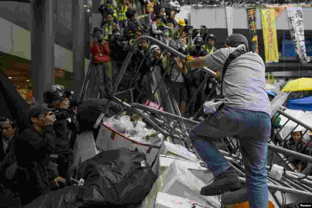 Para demonstran pro-demokrasi mengangkat barikade yang dipasang polisi ke eskalator dekat kantor-kantor pusat pemerintahan di distrik Admiralty, Hong Kong (1/12).