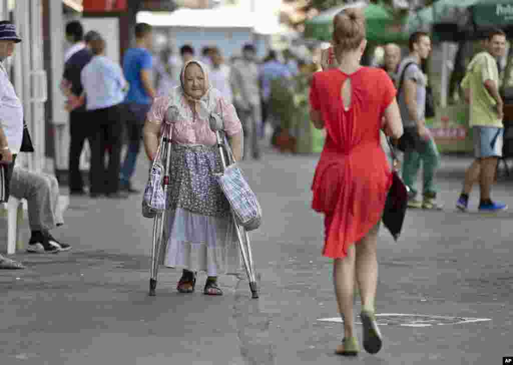 An elderly woman uses crutches to walk near the North Railway station in Bucharest, Romania.