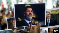 Les gens tiennent une photo du président égyptien Mohamed Morsi lors d'une cérémonie funèbre symbolique le 18 juin 2019 à la mosquée Fatih à Istanbul.
