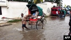 Un homme transporte des gens dans une charrette dans une rue inondée de Tuléar, à Madagascar, un jour après le passage du cyclone Haruna, 23 février 2013.