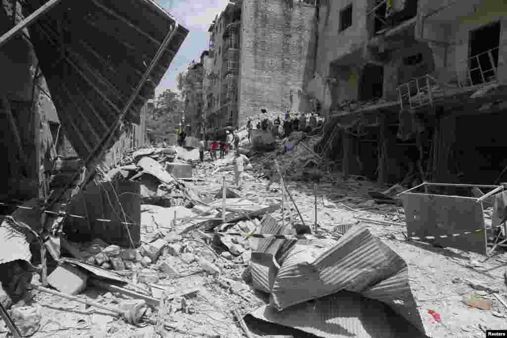 Men gather at a site hit by what activists said was a barrel bomb dropped by forces loyal to President Bashar al-Assad, in al-Qarlaq, Aleppo, May 29, 2014.
