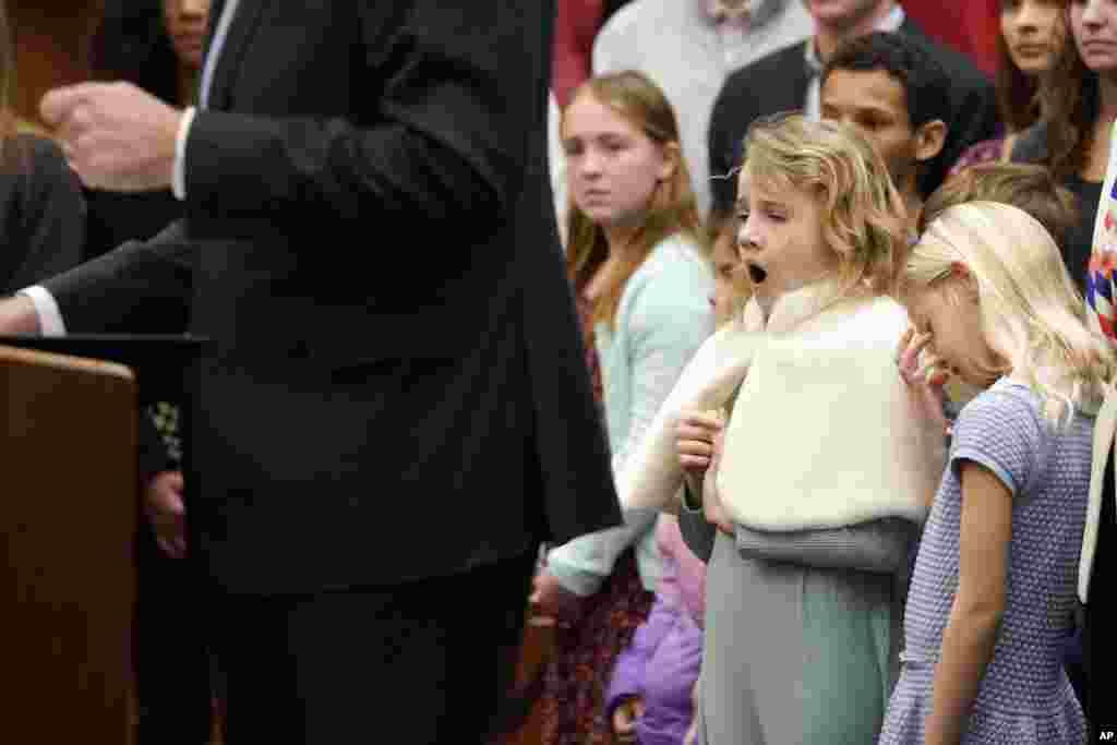 Two girls appear to be inattentive as Virginia Gov. Glenn Youngkin, left, speaks during an event at the Capitol in Richmond, Virginia.