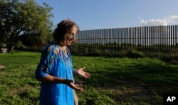 In this Sept. 17, 2015, photo, Dr. Eloisa Tamez walks in her backyard where the border fence passes through her property, in San Benito, Texas in the Rio Grande Valley. Tamez refused to cede her three acres in San Benito for the building of the wall, land that had been in her family for generations. A federal judge ruled in the government's favor, and Tamez was compensated $56,000.