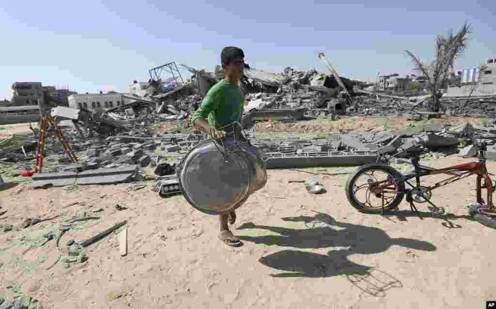 Seorang warga Palestina menyelamatkan apa yang ia bisa dari rumahnya setelah terkena serangan rudal Israel di Rafah, bagian selatan Jalur Gaza (9/7).&nbsp;(AP/Hatem Moussa)