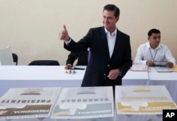 In this photo released by Mexico's presidential press office, Mexico's President Enrique Pena Nieto gives a thumbs up to photographers after voting during general elections in Mexico City, Sunday, July 1, 2018.