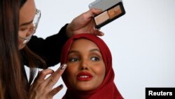 Model busana dan mantan pengungsi Halima Aden, merias wajahnya selama pemotretan di sebuah studio. (Foto: Reuters)