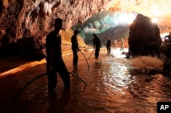 FILE - In this undated file photo provided by Royal Thai Navy on July 7, 2018, Thai rescue teams arrange a water pumping system at the entrance to a flooded cave complex where 12 boys and their soccer coach have been trapped since June 23, in Mae Sai, Chiang Rai province, northern Thailand.