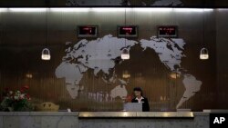 FILE - A staff member stands at the reception desk of a hotel, backdropped by a world map, in Pyongyang, North Korea, Oct. 23, 2014. The U.S. Thursday extended until Aug. 31, 2019, a ban for its citizens to travel to North Korea.