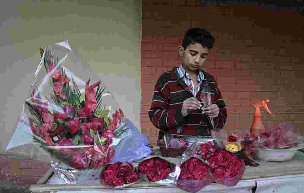 Seorang anak lelaki di Pakistan membantu merangkai bunga yang akan dijual pada hari Valentine di sebuah kios di pinggiran sebuah jalan kota Faisalabad (Reuters).