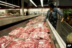 FILE - A shopper looks over pork products at a Costco store in Mountain View, Calif.