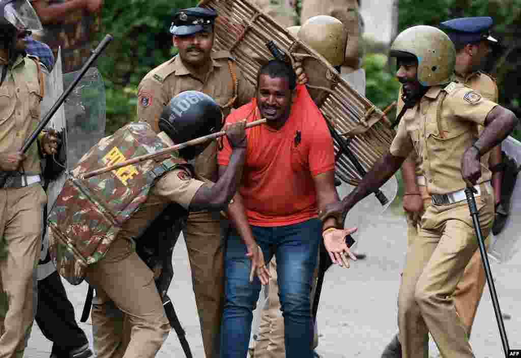 Indian police beat a Hindu activist as he pleads for his own safety as protesters rally against a Supreme Court verdict revoking a ban on women&#39;s entry to a Hindu temple, in Nilackal in southern Kerala state.