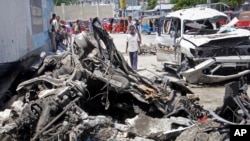 Somalis walk near the wreckage after a suicide car bomb attack in the capital Mogadishu, Somalia, May 22, 2019. 
