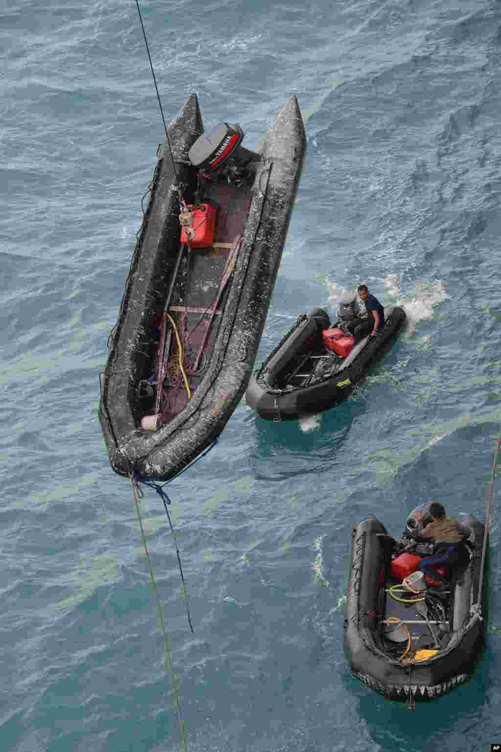 Para penyelam angkatan laut menunggu dalam perahu-perahu karet setelah melakukan operasi-operasi untuk mengangkat ekor pesawat AirAsia bernomor penerbangan 8501 di Laut Jawa (8/1). (AP/Adek Berry)