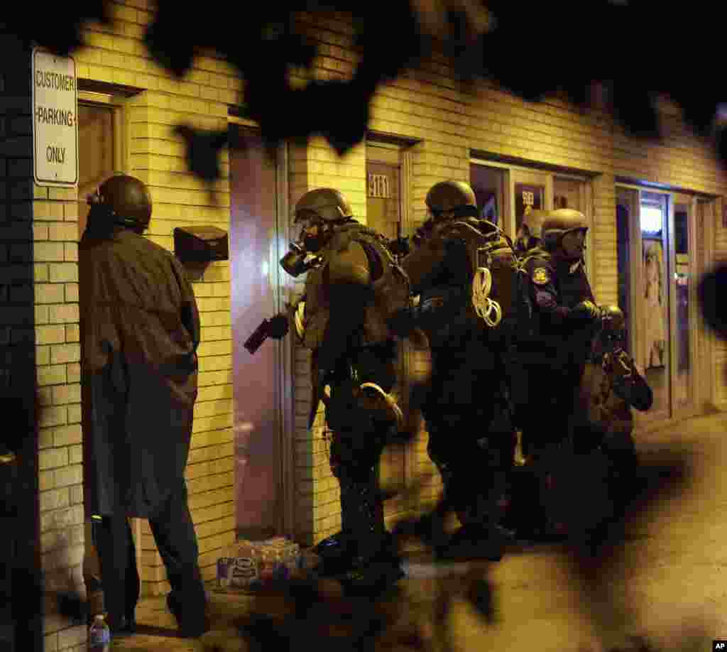 A law enforcement officers check a building, Aug. 17, 2014, after tear gas was fired to disperse protesters in Ferguson.
